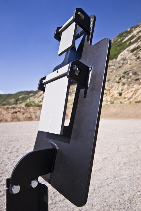 Tactical Torso1 Metal target stand with plates; set outdoors on gravel with mountains in background.