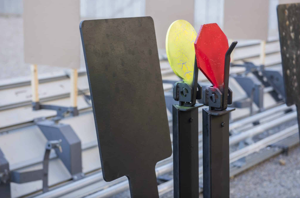 Close-up of steel shooting targets including black, yellow, and red plates on stands